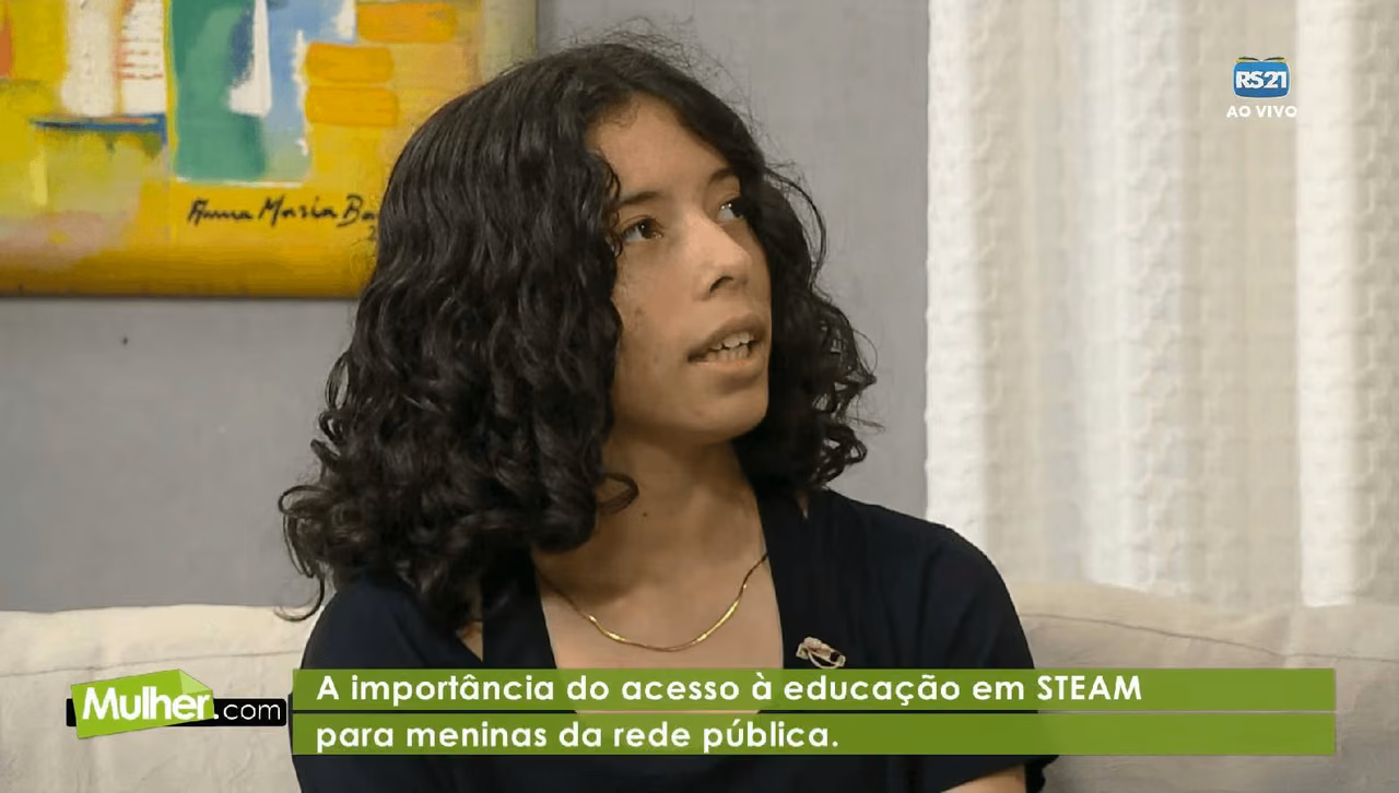 Quadro do programa Mulher.com com uma entrevistada e a legenda sobre o acesso das meninas da rede pública à educação STEAM.
